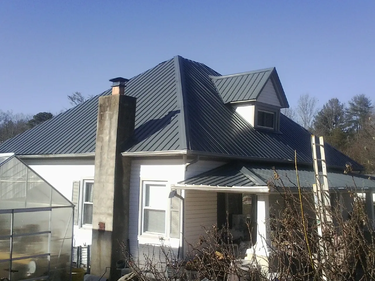 Dark blue standing seam metal roof on a white farmhouse with dormer — Slate & Tile Roof Repair by Roofing Brothers in Sterrett