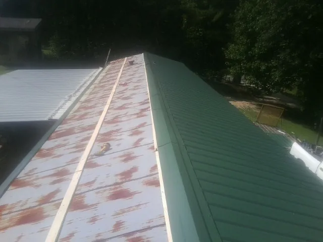 Old rusted panels beside newly installed green metal roofing — Wind Damage Roof Repair by Roofing Brothers in Sterrett