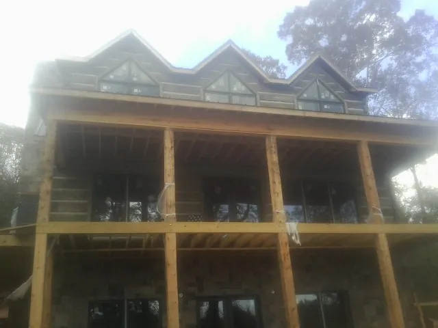 Dormers and porch framing on a large log home under construction — Roof Coating work by our crew in Sterrett