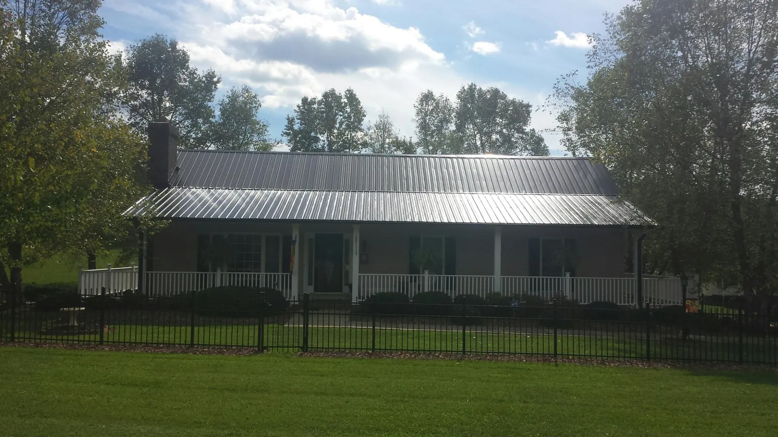 Gray metal roof on a brick ranch with a full width front porch — Gutter Guard Installation work by our crew in Sterrett