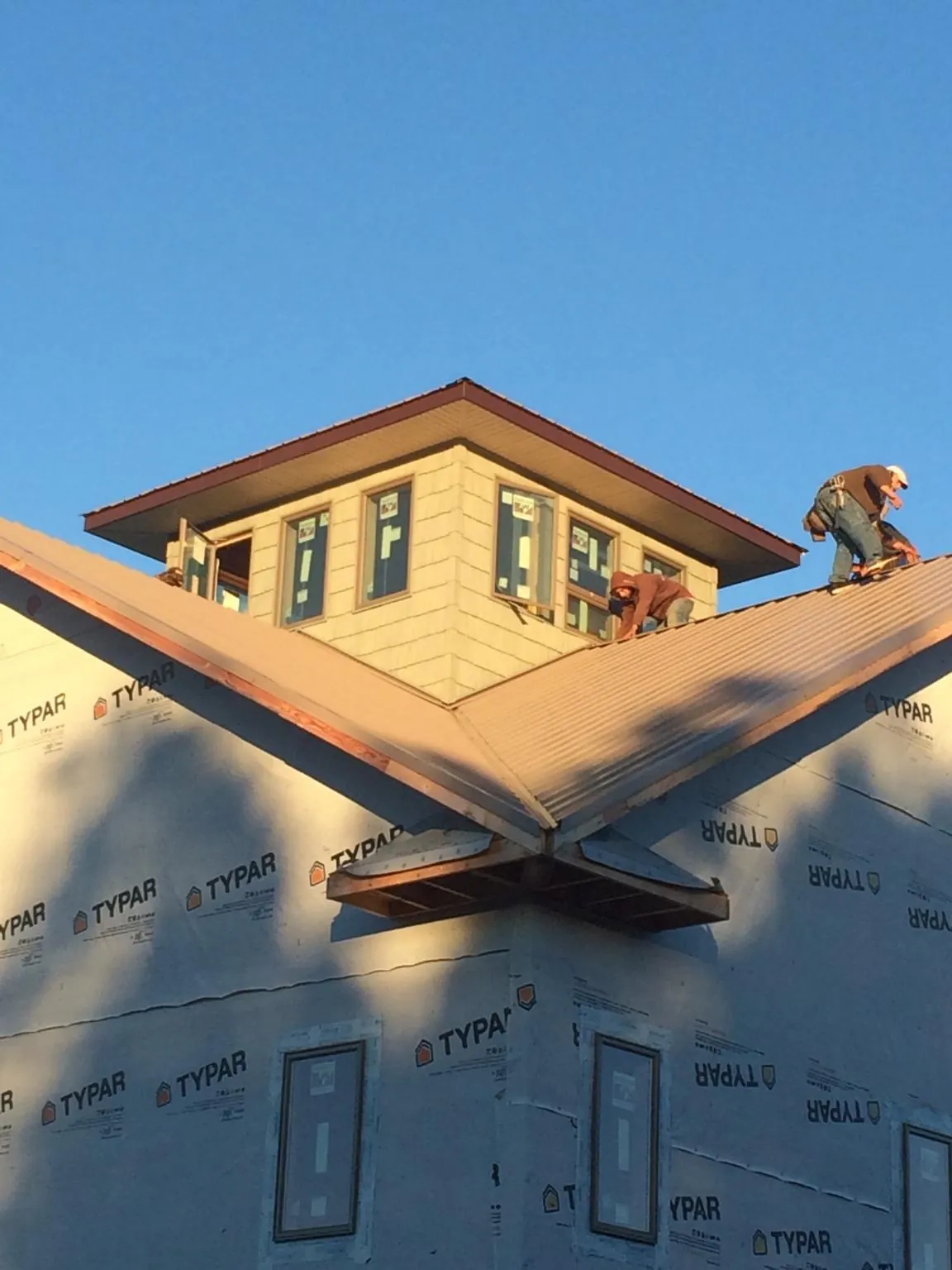 Roofers working around a rooftop cupola on a new metal roof at sunset — Roof Waterproofing in Sterrett by Roofing Brothers